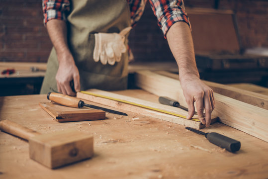 closeup photo of  cabinetmaker's tabletop.  Craftsman holding ruler  on wooden planknear other tools