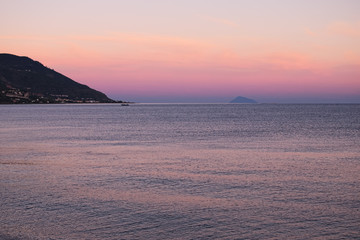 Fototapeta na wymiar Sunset at the Tyrrhenian Sea. Houses are located on seacoast. Marina di Patti. Sicily