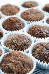Lots of sweet Brazilian candy Brigadeiro closeup. Delicious high-calorie chocolate dessert. Tasty sweet treats in white packaging. Homemade rustic sweets. The traditional Brazilian dessert.