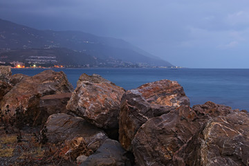 Large stones are designed to protect the coastline from the large waves. Morning mist descends from the mountain