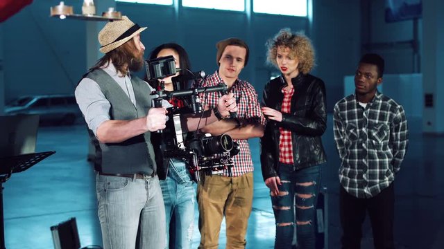 Man testing handheld camera gyro stabilizin gimbal, the director shows a difference between the mechanical and electronic three-axial video stabilizer