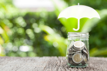 Coverage, insurance or Protection concept, coins in glass , umbrella nature background.
