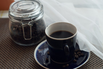 black coffee and a jar of coffee beans stand on the table