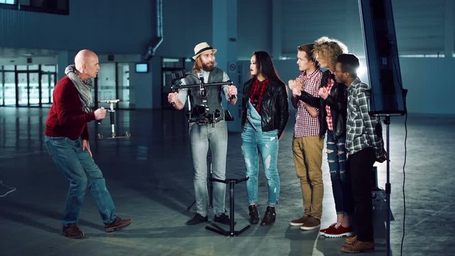 Man testing handheld camera gyro stabilizin gimbal, the director shows a difference between the mechanical and electronic three-axial video stabilizer