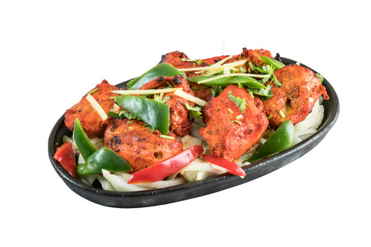 Chicken tikka kebab grilled in tandoor served on metal wooden plate isolated from background