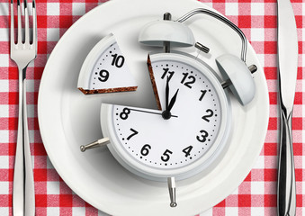 Time to eat concept, cut clock on plate. top view