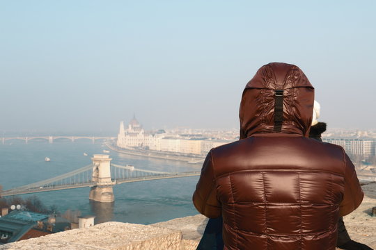 Person auf dem Burgpalast Budav&aacute;ri palota &uuml;ber Budapest Ungar geniest den herrlichen Ausblick auf die Stadt und die Donau und schaut in die Ferne auf die Sz&eacute;chenyi Kettenbr&uuml;cke.