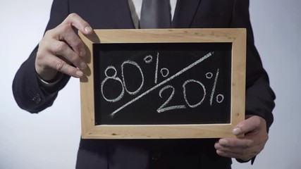 80 to 20 percent written on blackboard, man holding sign, Pareto principle