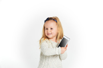 Naklejka premium Cute little girl smiling and uses a smartphone, phone.