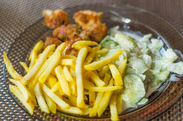 dinner with chips, frien meat and cucumber salad