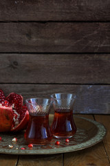 Fresh pomegranates and juice on copper plate. On wooden background. Free space for text. Place for wording