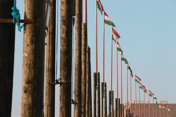 Obraz premium Flagge von Ungarn. Ungarische National Flaggen und Fahnen in Reihe auf Mast im Wind auf Burg Palast unter blauem Himmel von Budapest.