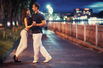 young couple dancing tango on the embankment - obrazy, fototapety, plakaty