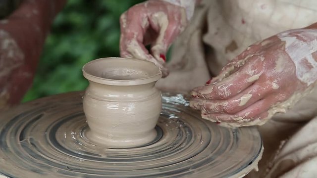 Hands of a potter and his apprentice. Man and woman makes a pot on pottery wheel. Woman is the pupil of a potter. Man and woman hands