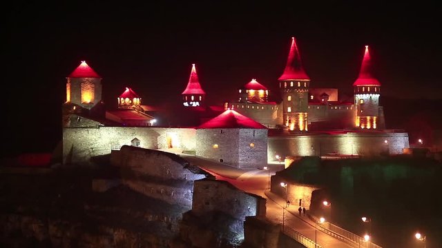 Old castle with red illumination at night, is former Ruthenian-Lithuanian castle and a later Polish fortress, located in historic city of Kamianets-Podilskyi, in historic region of Podolia in Ukraine