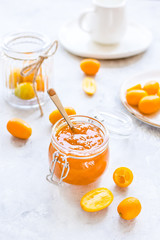 kumquat on plate and jam in jar at gray background