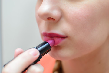 Girl paints her lips purple lipstick