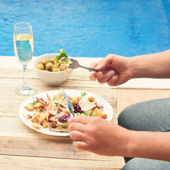 Female having dinner with champagne by the pool outdoor