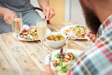 Closeup of friends having a dinner with champagne on terrace outdoor