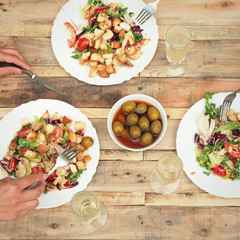 Salad, olives, glasses of champagne on vintage wooden table. Simple dinner concept