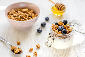 Homemade granola with blueberries in jar on white kitchen background