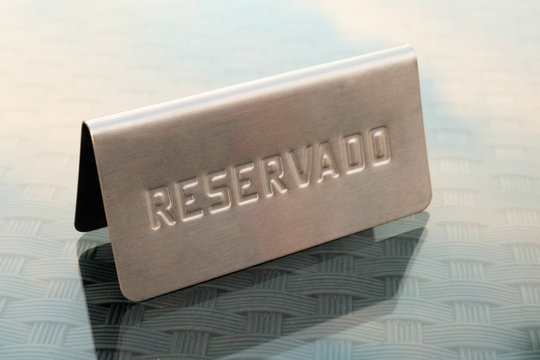 Metal reserved reservado sign on table in restaurant in Spain