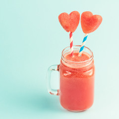 Watermelon smoothie in Mason jar with straws decorated with watermelon slices curved like heart symbols