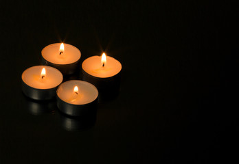 Four burning candles with reflection