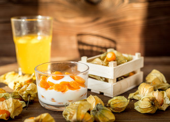 yogurt with physalis on wooden background