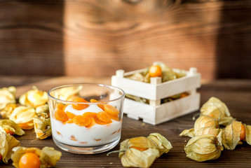 yogurt with physalis on wooden background