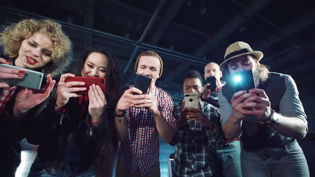 Diverse people bending to camera and taking shots on their smartphones.