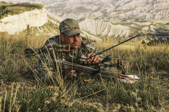 Man hunting in grass with bow