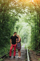 Loving couple in a tunnel of green trees on railroad