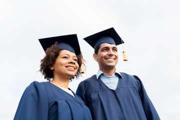 happy students or bachelors in mortarboards