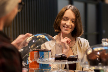 happy woman choosing cakes at vegan cafe