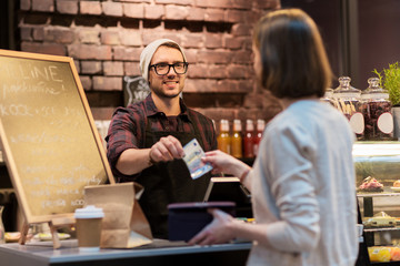 happy barman and woman paying money at cafe - obrazy, fototapety, plakaty