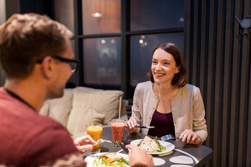 Obraz na płótnie Canvas happy couple eating dinner at vegan restaurant