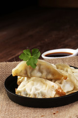 A plate of Japanese gyoza dumplings sitting on a rustic wooden t