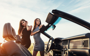 Beautiful two women sitting in a convertible, enjoying