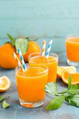 Orange juice in glass and fresh fruits with leaves on wooden background, vitamin drink or cocktail