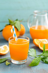 Orange juice in glass and fresh fruits with leaves on wooden background, vitamin drink or cocktail