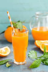 Orangensaft im Glas und frische Früchte mit Blättern auf Holzhintergrund, Vitamingetränk oder Cocktail
