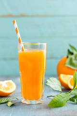Orange juice in glass and fresh fruits with leaves on wooden background, vitamin drink or cocktail