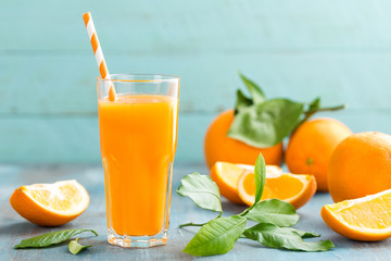 Orangensaft im Glas und frische Früchte mit Blättern auf Holzhintergrund, Vitamingetränk oder Cocktail