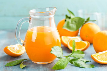 Orange juice in glass and fresh fruits with leaves on wooden background, vitamin drink or cocktail