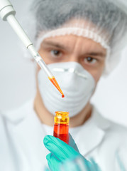 Keen scientist with brown eyes pipettes orange sample