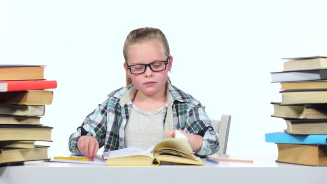 Girl sits at the table leafing through the book. White background