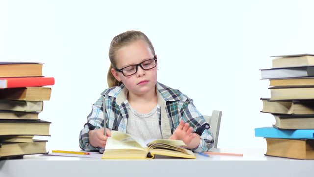 Girl sits at the table leafing through the book. White background