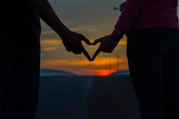 silhouette of couple in love.Focus on hands at sunset.