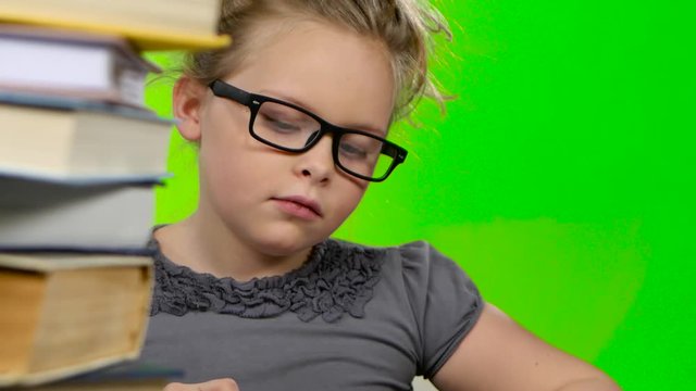 Girl leafing through a book of interesting looks for another. Green screen. Close up